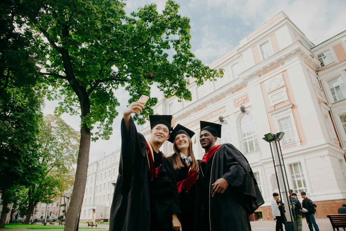 Three international graduates celebrating together outside their university